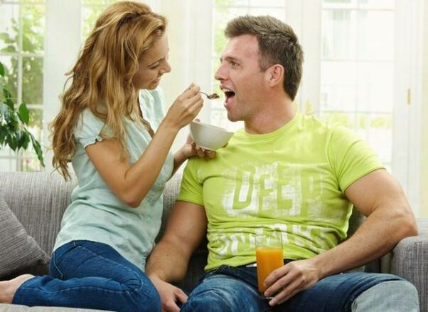една жена храни мъж с продукти за повишаване на потентността